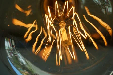 Electricity current inside a retro crystal clear light bulb. Stock Photos