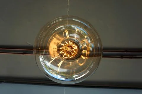 Electricity current inside a retro crystal clear light bulb. Stock Photos