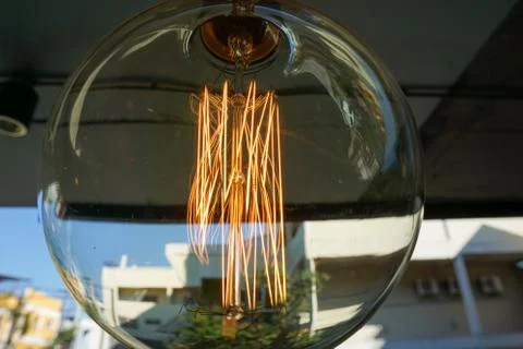 Electricity current inside a retro crystal clear light bulb. Stock Photos