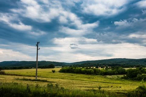An electricity pole in a wheat field under a dramatic sky Stock Photos