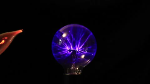 Electricity from a tesla coil based violet wand jumps to red light bulb Stock Footage 46940773