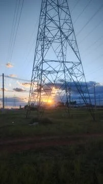 Electricity tower at sunset with withe clouds in background Stock Photos