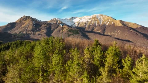 An electricity windmill is revealed in between mountain trees 動画素材 174160584