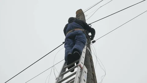 Electricity work, man repairs electric pole wearing all the safety equipment Stock Footage 126994468