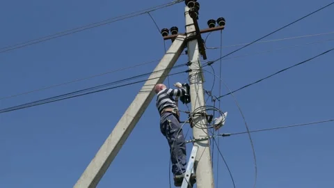 Electricity work, man repairs electric pole wearing all the safety equipment Stock Footage 146747436
