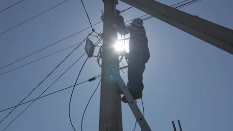 Electricity work, man repairs electric pole wearing all the safety equipment Stock Footage 148047842