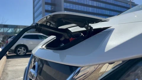 Electro Car is charging against the backdrop skyscrapers city parking lot. Stock Footage 238533277