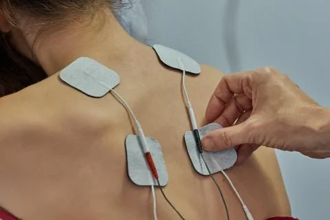 Electro stimulation in physical therapy to a young woman. Medical check at th Stock Photos
