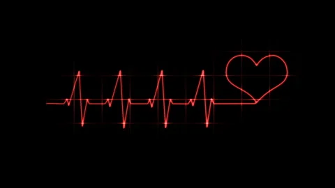 Electrocardiogram with transition to heart.Red ECG scale on a black background Stock Footage 275076624