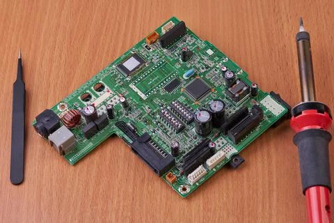 Electronic board repair component held with tweezers by an engineer over a gr Stock Photos