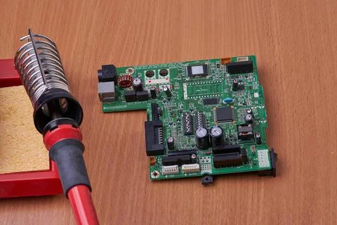 Electronic board repair component held with tweezers by an engineer over a gr Stock Photos