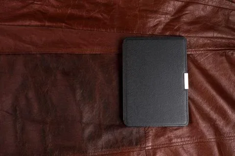 Electronic book in the case on leather background Stock Photos