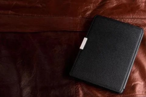 Electronic book in the case on leather background Stock Photos