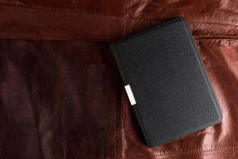 Electronic book in the case on leather background Stock Photos