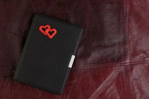Electronic book in case with two hearts on leather background. Romantic book  Stock Photos