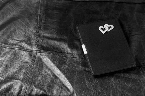 Electronic book in case with two hearts on leather background. Romantic book  Stock Photos