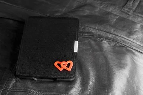 Electronic book in case with two hearts on leather background. Romantic book  Stock Photos