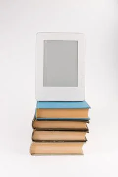 Electronic book on the top of the stack of regular old books isolated on whit Stock Photos