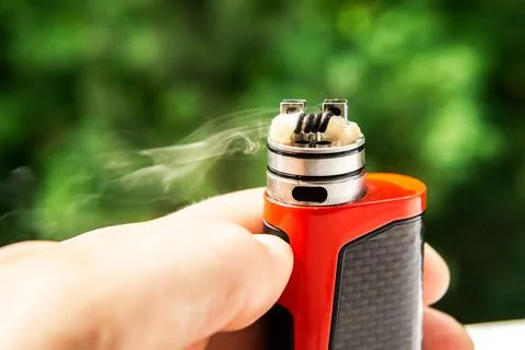 Electronic cigarette on the background of trees, visible spiral wool and stea Stock-Fotos