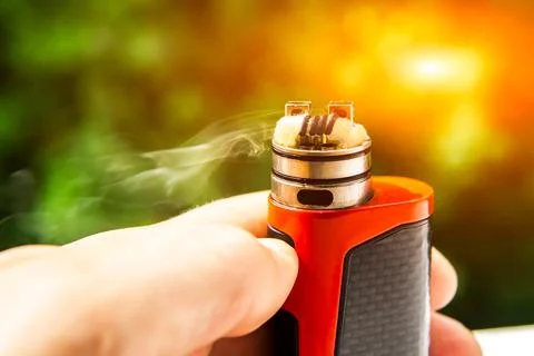 Electronic cigarette on the background of trees, visible spiral wool and stea Stock Photos