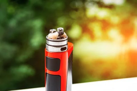 Electronic cigarette on the background of trees, visible spiral wool and stea Stock Photos