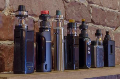 Electronic cigarette on a background of vape shop. E-cigarette for vaping. Stock Photos
