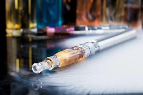 Electronic cigarette with e-liquid bottles in background Foto stock