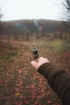 Electronic cigarette in one hand from which vapor comes out Stock Photos