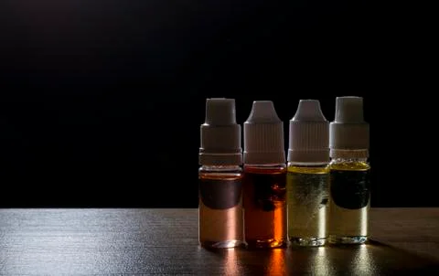 Electronic cigarette, vaping device with e liquid background. Stock Photos