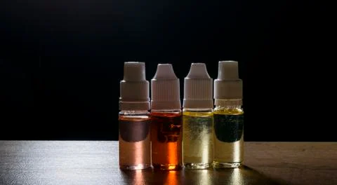 Electronic cigarette, vaping device with e liquid background. Stock Photos