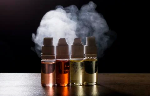 Electronic cigarette, vaping device with e liquid background. Stock Photos