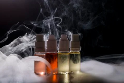 Electronic cigarette, vaping device with e liquid background. Stock Photos