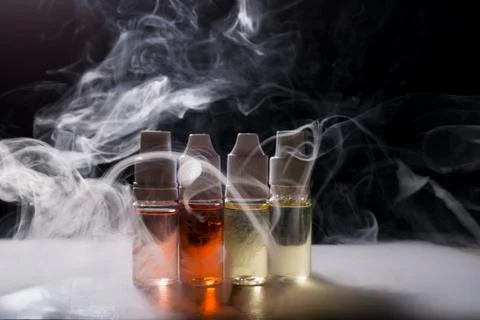 Electronic cigarette, vaping device with e liquid background. Stock Photos