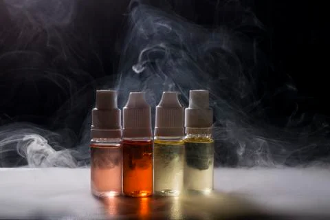 Electronic cigarette, vaping device with e liquid background. Stock Photos