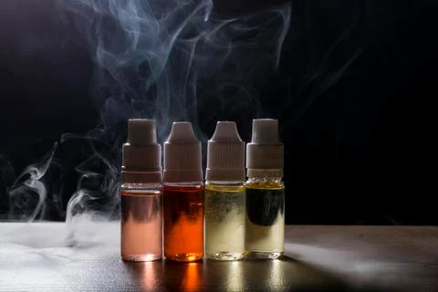 Electronic cigarette, vaping device with e liquid background. Stock Photos