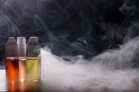 Electronic cigarette, vaping device with e liquid background. Stock Photos