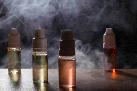 Electronic cigarette, vaping device with e liquid background. Stock Photos