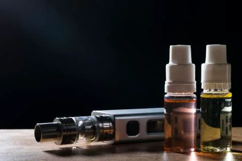 Electronic cigarette, vaping device with e liquid background. Stock Photos