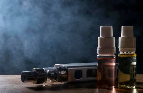 Electronic cigarette, vaping device with e liquid background. Stock Photos