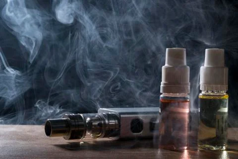 Electronic cigarette, vaping device with e liquid background. Stock Photos