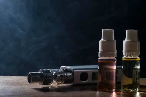 Electronic cigarette, vaping device with e liquid background. Stock Photos
