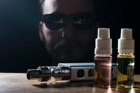 Electronic cigarette, vaping device with e liquid background. Stock Photos