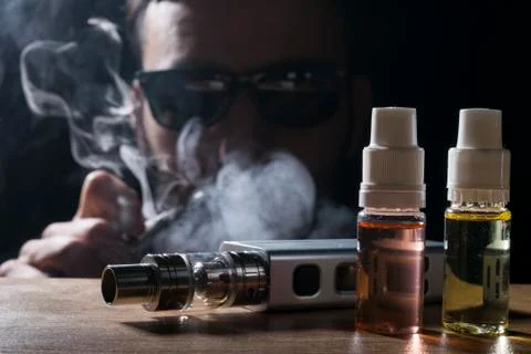 Electronic cigarette, vaping device with e liquid background. Stock Photos