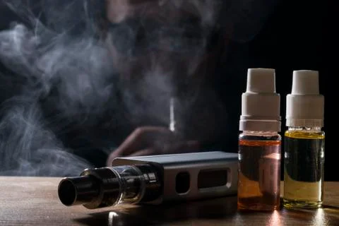Electronic cigarette, vaping device with e liquid background. Stock Photos