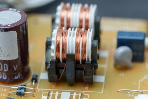 Electronic circuit board components showcasing coils and capacitors on a ye.. Stock Photos