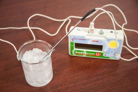 Electronic digital probe measuring temperature of ice inside glass beaker Stock Photos