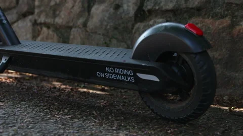 Electronic E-Scooter Bird Sits alongside Rustic Brick Wall  to Reveal Handlebars Stock Footage 130866727