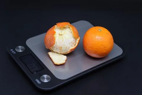 Electronic kitchen scale with two tangerines, calorie counting. Stock Photos