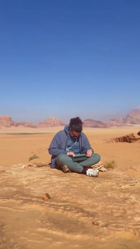 Electronic musician composes on a tablet in the red desert landscape of Wadi Rum Stock Footage 292922286