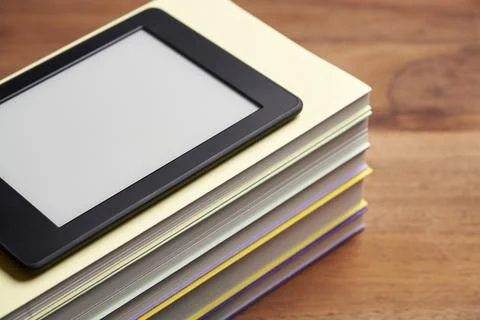 Electronic reader with blank screen on a pile of books on a wooden desk Foto stock